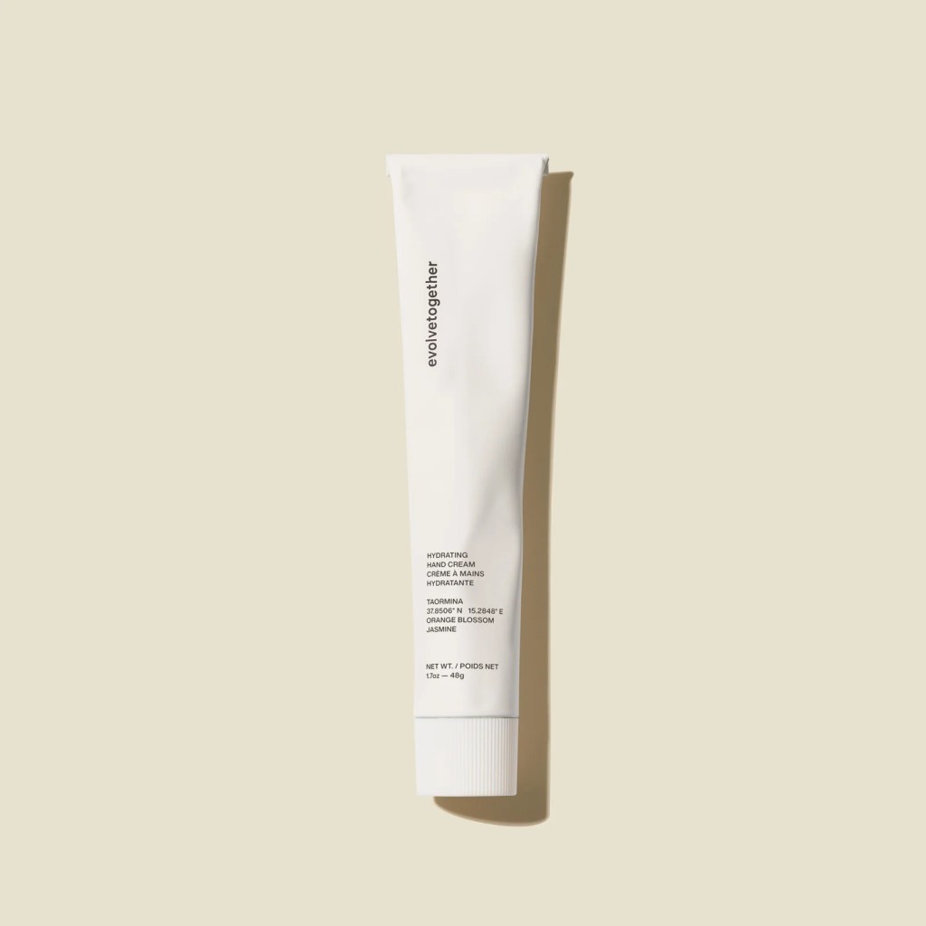 A tube of hydrating hand cream labeled 'evolve together' featuring ingredients like orange blossom and jasmine, set against a neutral background.