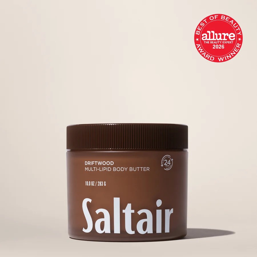 A brown jar of Saltair Driftwood Multi-Lipid Body Butter on a neutral background. The jar is labeled with 'Saltair' and includes details about its size and features.