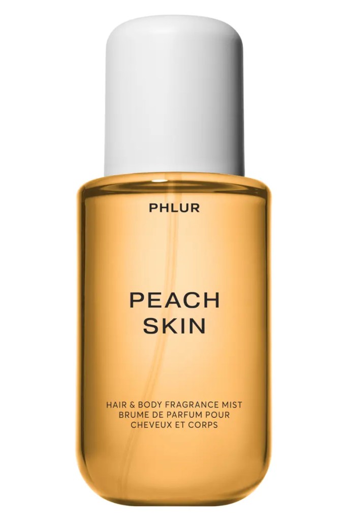 A bottle of PHLUR Peach Skin hair and body fragrance mist with a white cap and translucent amber liquid.