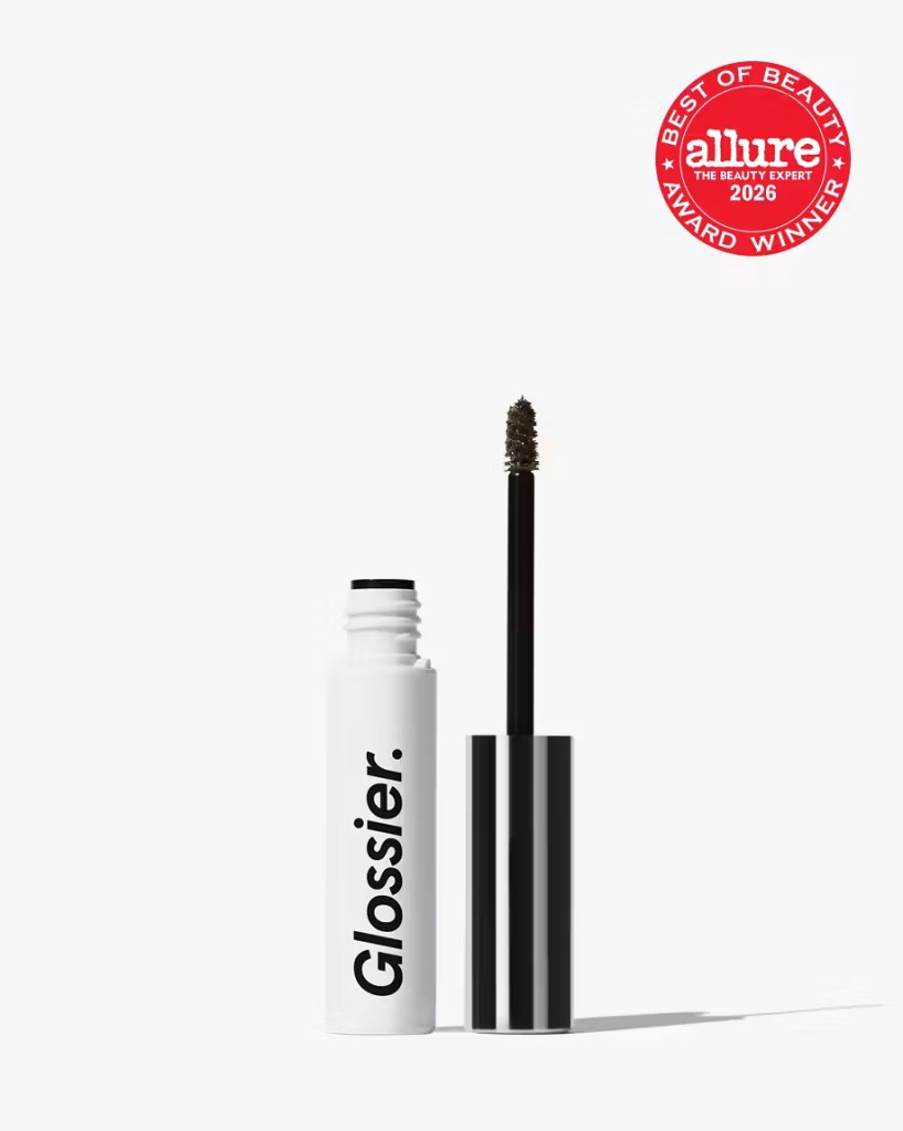 A Glossier mascara tube with a white body and black text, slightly open to reveal a black wand with bristles, accompanied by an Allure award badge stating 'Best of Beauty 2026'.