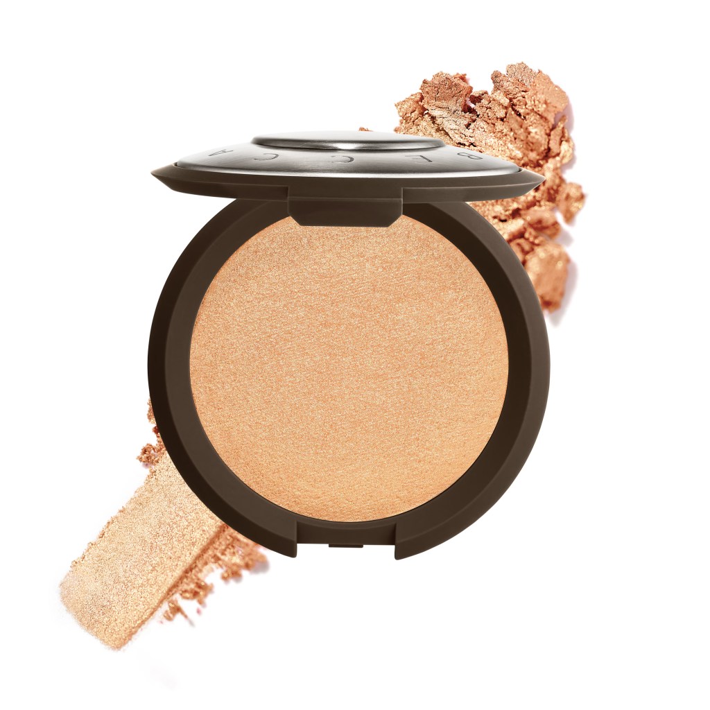 A round compact of shimmery bronzer with a light golden shade, accompanied by a scattered pile of the product.