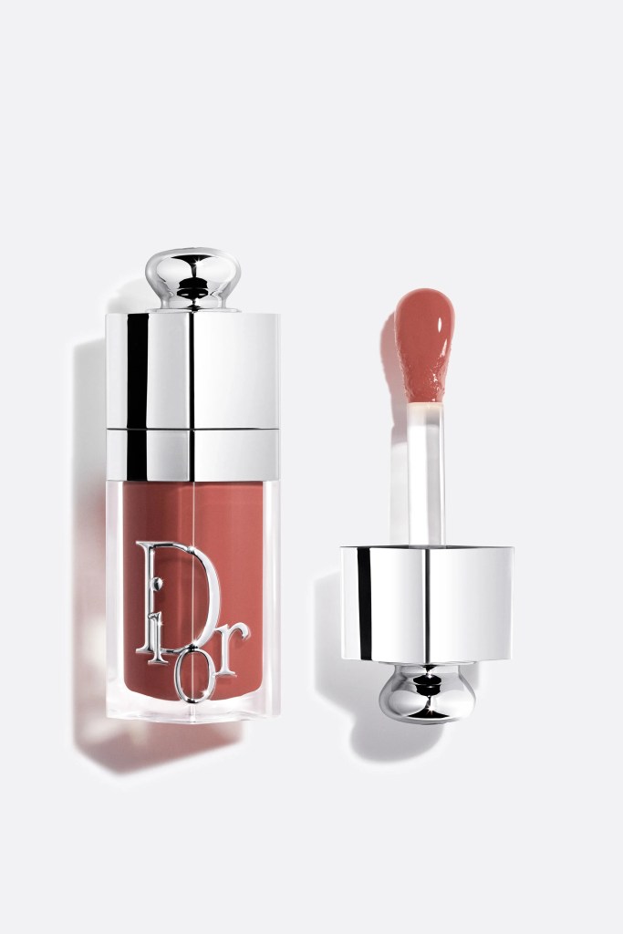 A bottle of Dior lip product with a silver cap, alongside an applicator with a soft tip covered in a rosy color.