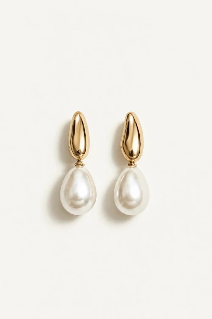Gold teardrop earrings with white pearls attached, elegantly displayed on a neutral background.