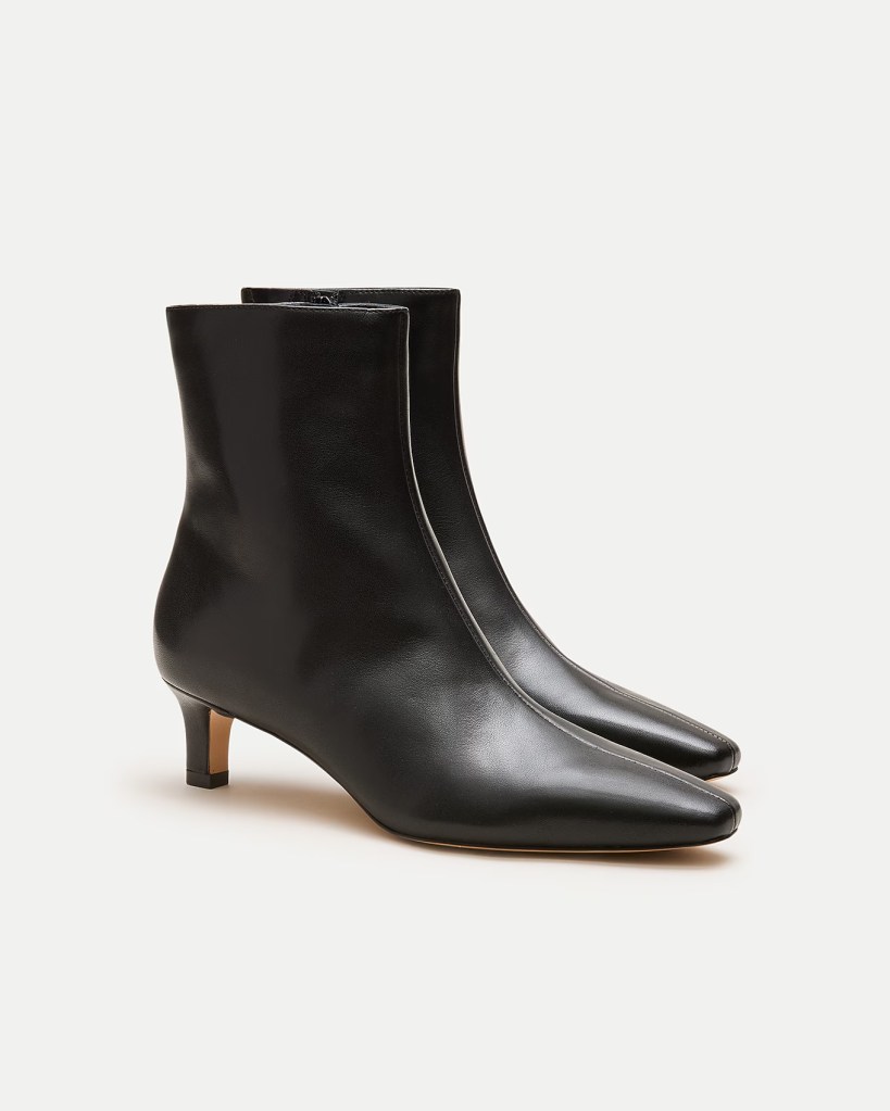 A pair of stylish black leather ankle boots with a pointed toe and a low heel.