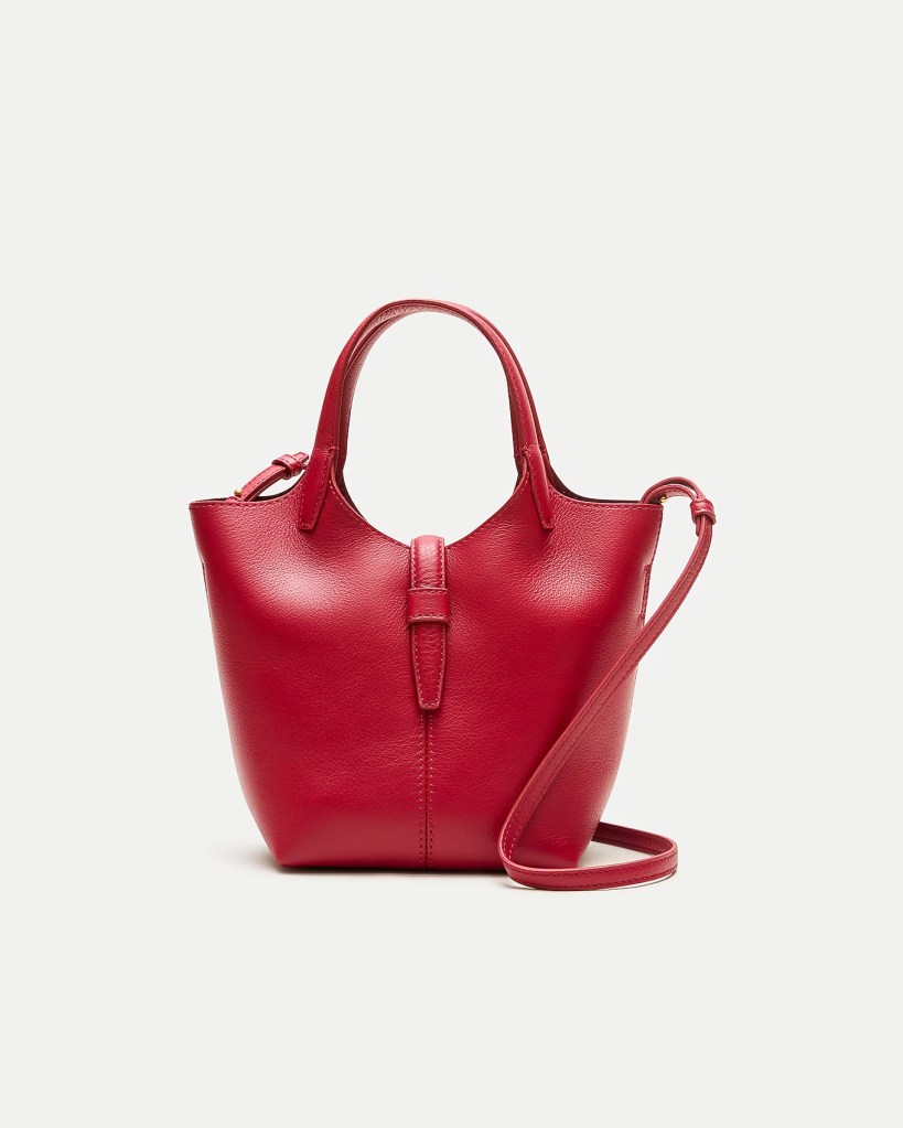 A stylish red leather handbag with a structured design, featuring dual handles and a detachable shoulder strap.