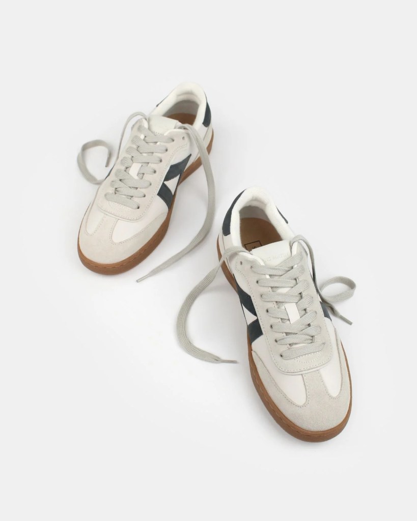 A pair of white and navy athletic sneakers with gum soles, featuring laces and a minimalist design.