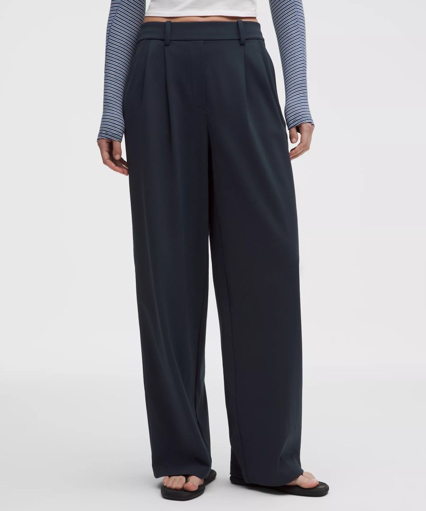 A person wearing wide-leg dark trousers paired with a striped long-sleeve top and flat sandals.