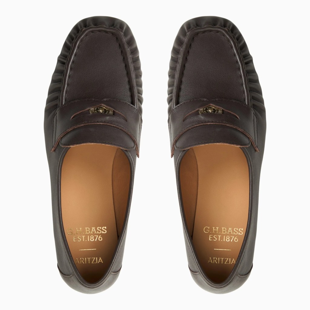A pair of dark brown leather loafers featuring a classic design with decorative stitching and a small emblem on the front.